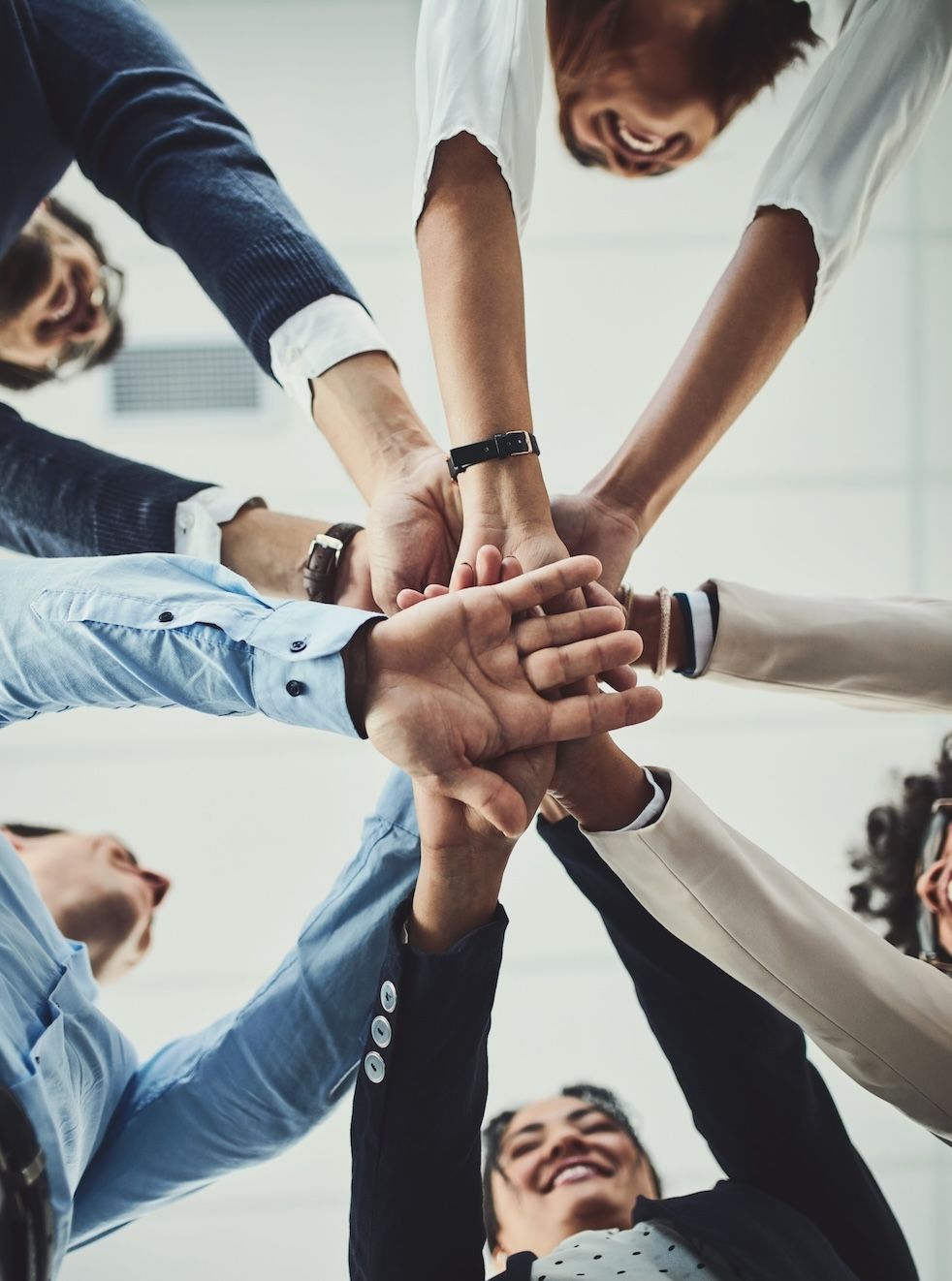 Close-up view of diverse hands stacked together in a gesture of unity and teamwork, representing collaboration and inclusive work culture