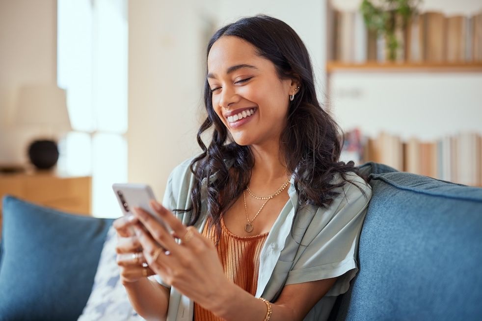 Smiling woman looking at smartphone, representing customer engagement and technology-driven solutions